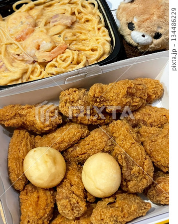 Crispy Korean fried chicken with golden coating served alongside a plate of spaghetti with rich sauce, creating a combination of savory crunch and flavorful pasta in one satisfying meal 134486229
