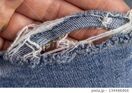 torn jeans from long-term wear, part of blue jeans made of cotton fabric that are frayed and torn from long-term wear and use 134486468