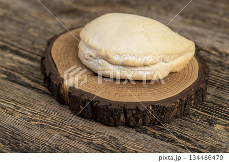 a whole shortbread bun with cottage cheese filling on a wooden board on the table, soft pastries stuffed with cottage cheese and sugar are on the board 134486470