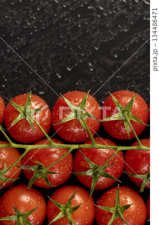 wet ripe red round tomatoes on a black slate board, sweet fresh round tomatoes covered with water droplets lie on a board after harvesting 134486471