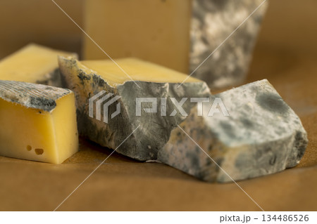 an old spoiled orange cheese with colorful mold, an inedible and dangerous cheese that was spoiled during the improper storage, the cheese is covered with mold dangerous to health an old spoiled orange cheese with colorful mold, an inedible and dangerous cheese that was spoiled during the improper storage, the cheese is covered with mold dangerous to health 134486526