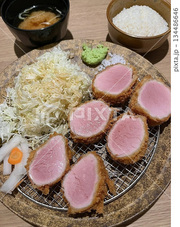 Crispy tonkatsu, a Japanese-style breaded and deep-fried pork cutlet, served with shredded cabbage and drizzled with savory sauce. A delightful balance of crunchy texture and juicy meat. 134486646