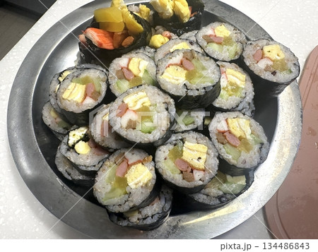 Delicious kimbap rolls filled with fresh vegetables, seasoned rice, and savory proteins, all wrapped in crisp seaweed. A perfect combination of flavor and texture in every bite. 134486843