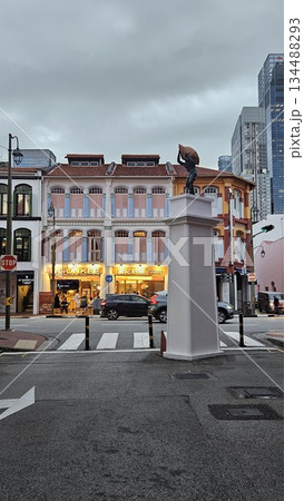 A dynamic statue anchors a lively street scene where pastel shophouses, modern towers 134488293