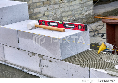 Wooden hammer, measuring level for fitting building blocks of bricks 134488797