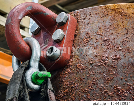 Rusted metal hook showing wear at a construction site in the afternoon light with tools nearby 134488934