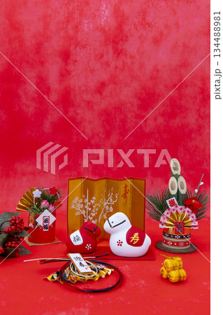鮮やかな赤背景に紅白の午の置物と門松、金屏風などを並べた豪華な正月イメージ 134488981