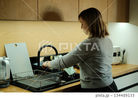 Woman rinses reusable cutting board under kitchen tap. Conscious housekeeping, water conservation, sustainable living. Woman rinses reusable cutting board under kitchen tap. Conscious housekeeping, water conservation, sustainable living. 134489133