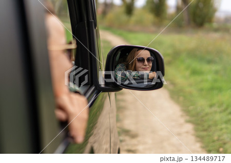 Woman car mirror reflection traveling dirt road adventure vacation trip Woman car mirror reflection traveling dirt road adventure vacation trip 134489717