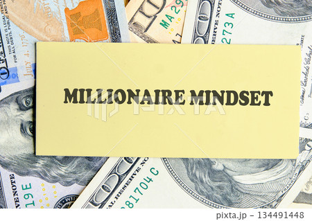 A yellow card displays the words Millionaire Mindset, surrounded by a vibrant and textured background of One Hundred Dollar bills, evoking thoughts of ambition and achievement A yellow card displays the words Millionaire Mindset, surrounded by a vibrant and textured background of One Hundred Dollar bills, evoking thoughts of ambition and achievement 134491448