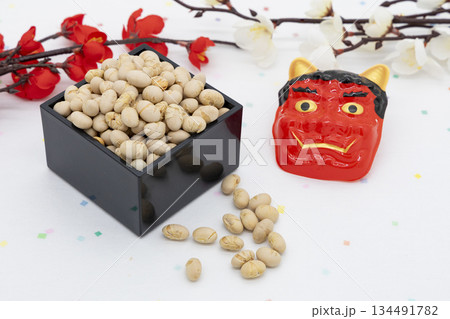 カラフル和紙背景に紅白の梅と枡入り煎り大豆、赤鬼のお面を並べた節分イメージ 134491782