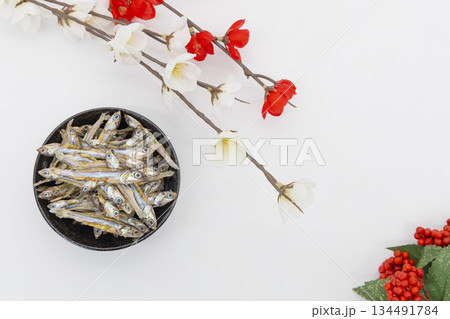 白背景に俯瞰で置かれたおせち料理の田作りと紅白の梅、南天　 正月イメージ 134491784
