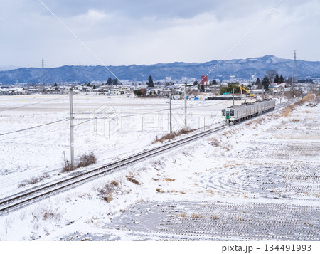 【山形線】冬の田園風景を走行する普通列車 134491993