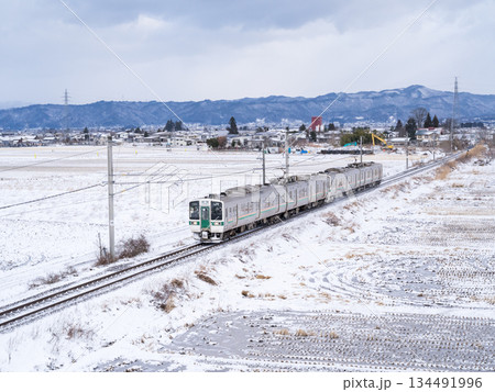 【山形線】冬の田園風景を走行する普通列車 134491996