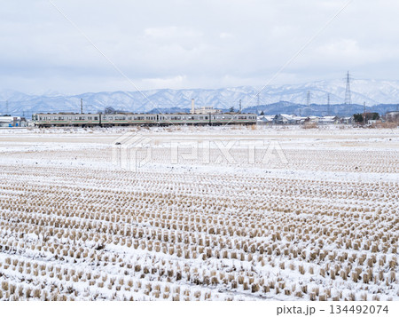 【山形線】冬の田園風景を走行する普通列車 134492074