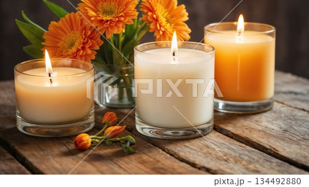 Cozy lit candles and orange flowers on rustic wood Cozy lit candles and orange flowers on rustic wood 134492880