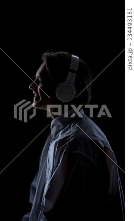 Smiling man in headphones standing on black background. 134493181