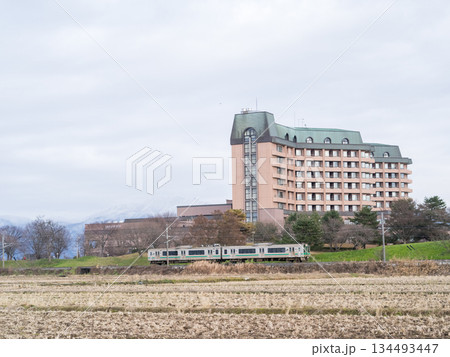 【山形線】冬枯れの田園風景を走行する普通列車 134493447