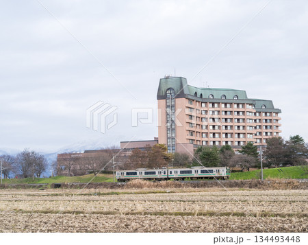 【山形線】冬枯れの田園風景を走行する普通列車 134493448
