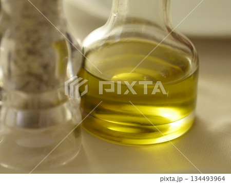 Bottle of olive oil sits on a table next to a salt shaker Bottle of olive oil sits on a table next to a salt shaker 134493964