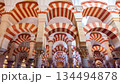 Interior of Mosque-Cathedral of Cordoba Spain featuring iconic red and white striped Moorish arches, ancient stone columns and historic Islamic architecture inside the famous Mezquita landmark. 134494878