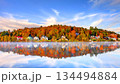 Scenic autumn landscape of Saranac Lake village in Adirondack Mountains New York featuring colorful fall foliage, historic waterfront houses and perfect misty water reflection under blue sky. 134494884
