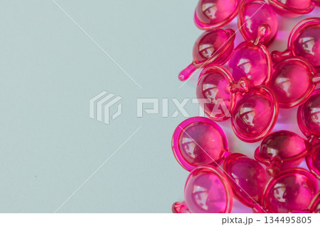 Bright pink hair capsules border on the left side of a clean light background, providing generous copy space for text, promotional cosmetic health care advertising Bright pink hair capsules border on the left side of a clean light background, providing generous copy space for text, promotional cosmetic health care advertising 134495805