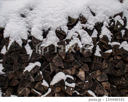 A woodpile. Old black firewood under fluffy snow. 134496591