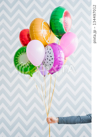 Colorful Fruit Balloons In Hand On Zigzag Wall Colorful Fruit Balloons In Hand On Zigzag Wall 134497012