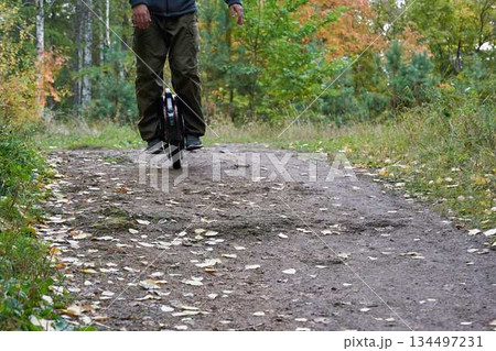 man rides down the trail on a monocycle. close up unicycle. man rides down the trail on a monocycle. close up unicycle. 134497231
