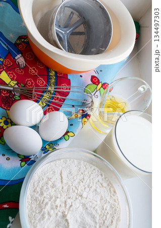 raw ingredients for pancakes are laid out on a multi-colored tablecloth raw ingredients for pancakes are laid out on a multi-colored tablecloth 134497303