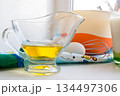 sunflower oil in a glass transparent oiler on a white windowsill next to the ingredients for pancakes 134497306