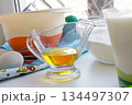 sunflower oil in a glass transparent oiler on a white windowsill next to the ingredients for pancakes 134497307