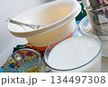 raw ingredients for pancakes are laid out on a multi-colored tablecloth and white background 134497308
