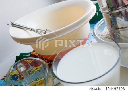 raw ingredients for pancakes are laid out on a multi-colored tablecloth and white background 134497308