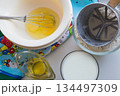 raw ingredients for pancakes are laid out on a multi-colored tablecloth and white background 134497309