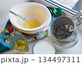 raw ingredients for pancakes are laid out on a multi-colored tablecloth and white background 134497311