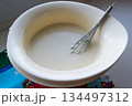 the finished pancake batter in a white bowl with a metal whisk 134497312