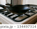 black cast-iron pan is on a gas stove 134497314