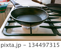 black cast-iron pan is on a gas stove 134497315
