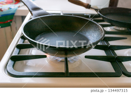 black cast-iron pan is on a gas stove black cast-iron pan is on a gas stove 134497315