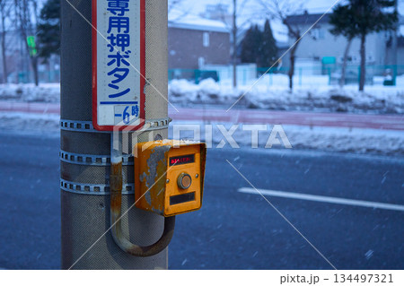 塗装が剥げた古い押しボタン信号と雪が降る冬の道路の風景 134497321