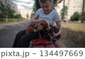 Animal theme is a lonely old woman best friend. Caucasian 90 years old senior female is happy to spend time with her pet small dachshund dog, holding her in her arms, hugging hugs and kisses outdoor 134497669