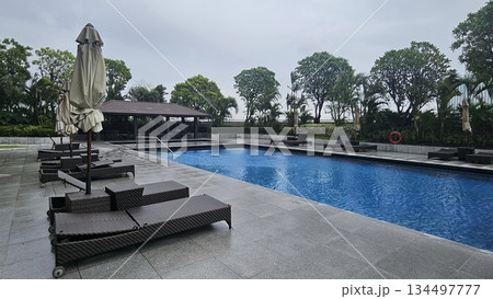A serene poolside with wicker loungers, closed umbrellas 134497777