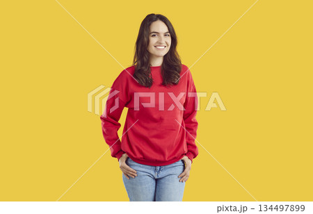 Smiling young woman standing with her hands on hips Smiling young woman standing with her hands on hips 134497899