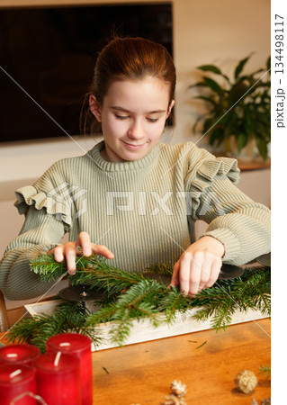 Girl preparing Advent wreath with fir branches at home Girl preparing Advent wreath with fir branches at home 134498117