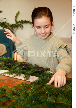 Girl preparing Advent wreath with fir branches at home 134498119