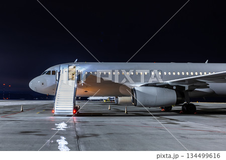 Modern passenger plane with boarding steps at the night airport 134499616