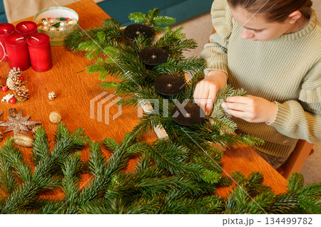 Child arranging advent wreath with candles and pine branches 134499782