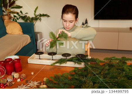 Girl preparing Advent wreath with fir branches at home 134499795